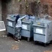 A still image from the video showing a woman rifling through bins in Lye