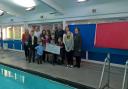 Alison and Dave Banner with Daniel's brother Jake and sister Katie, plus family and friends who took part in the sponsored swim, and event organiser Michael Harley from Learning4life, pictured handing the money over to Birmingham Women and Children